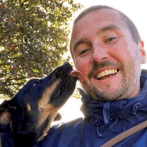 Joseph laughing while a young dog licks his cheek