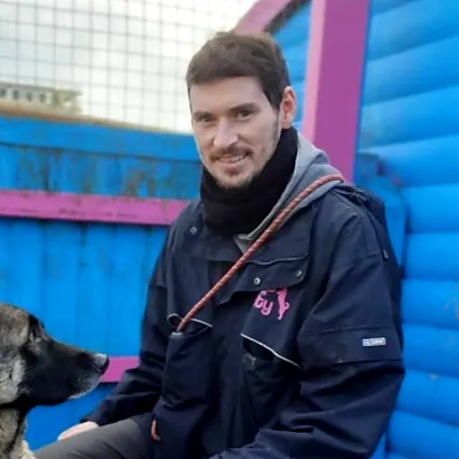 Stuart crouched down, holding a German Shepherd's paw